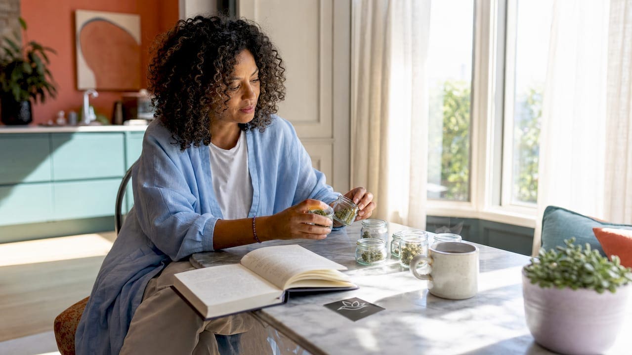 Woman examining jars of cannabis buds at home